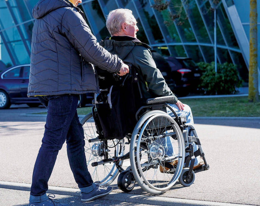 Image of a man using the Empulse R20 Power Assist Device - Lightweight, portable power assist for manual wheelchairs, designed to reduce caregiver strain and improve mobility.