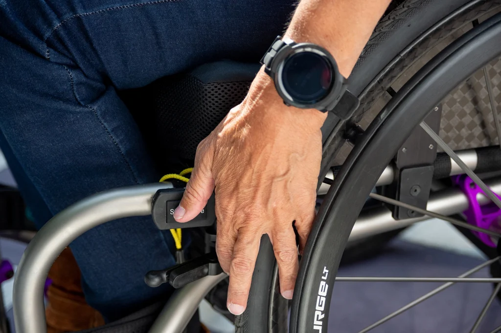 Close up image of a man utilizing his Smart Drive MX2+ Switch Control - Joystick controller for powered wheelchairs, featuring multiple scan and control options for users with limited mobility.