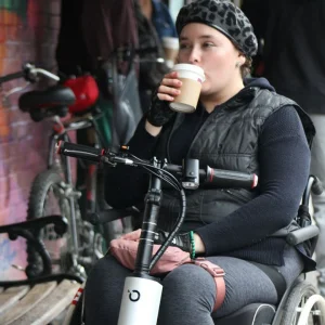 Woman utilizing her Cheelcare Companion while relaxing and sipping on a cup of coffee