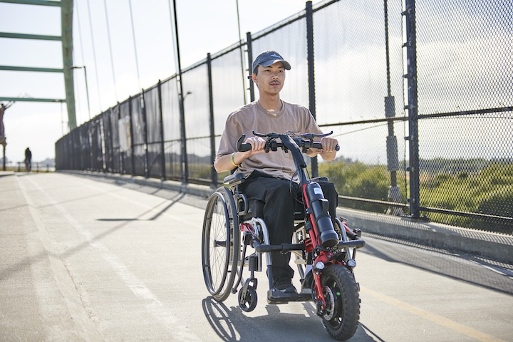 Front view of an adventurous man driving his Rio Firefly 2.5 - Electric Power Assist for Manual Wheelchairs through a scenic trail.