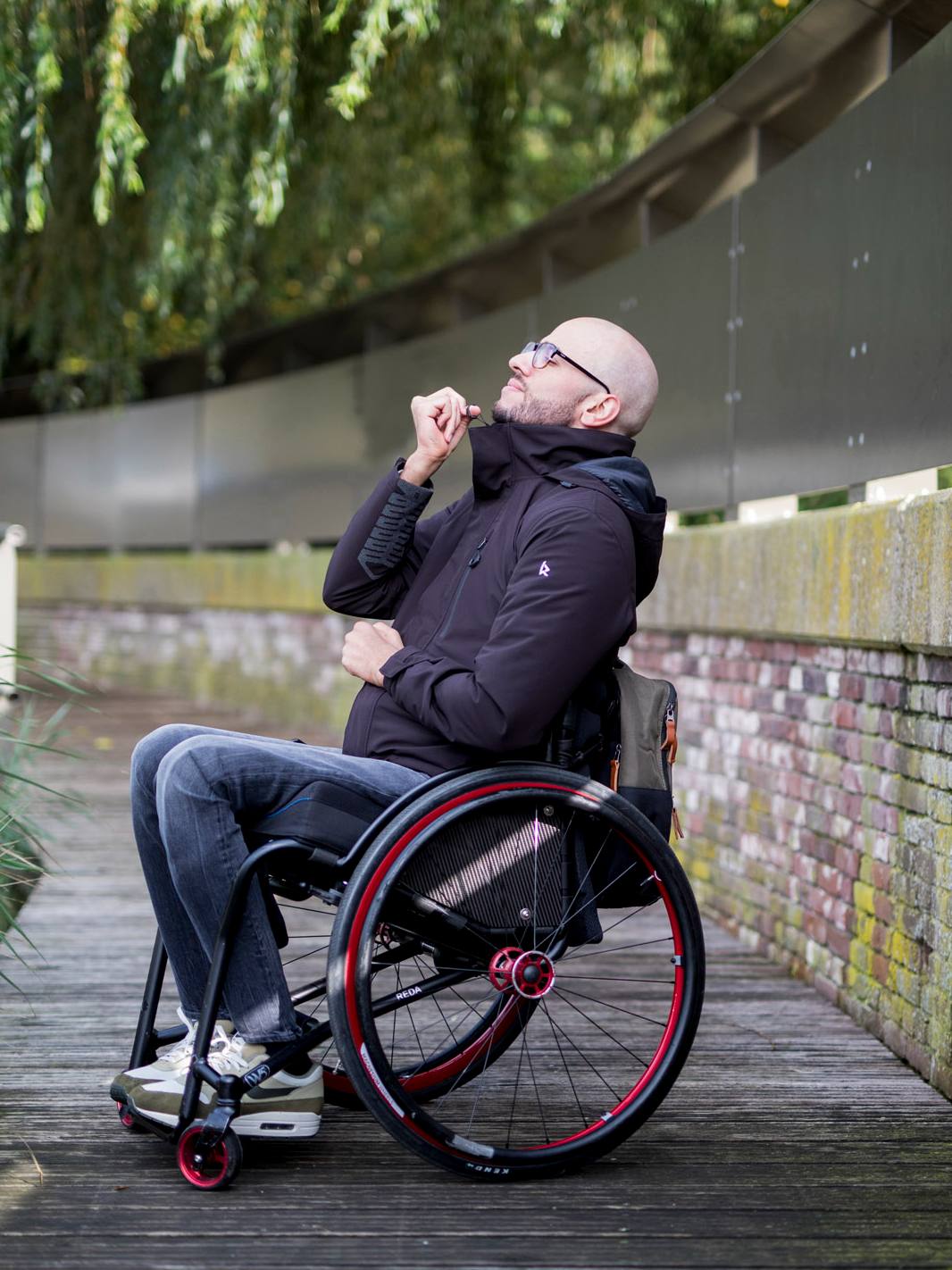 Image of a man in his wheelchair while wearing the black Kinetic Balance QT Jacket - Lightweight, quilted jacket designed for wheelchair users, offering warmth and comfort during cooler weather.