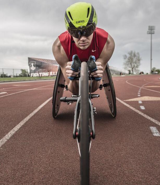 Front view of athletic young man racing on a track inside the quick Top End NRG Full Carbon Racing Chair.