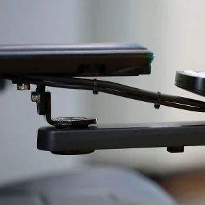Side view of the Retractable Joystick Mount on wheelchair. A sleek, metal joystick mount attached to a wheelchair armrest. The joystick can be easily swung outwards or retracted sideways for improved accessibility.